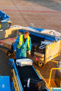 AMSTERDAM, NETHERLANDS - NOVEMBER 08: 08 Kasım 2014 tarihinde Hollanda 'nın Amsterdam Schiphol havaalanında bir uçaktan bavul indiren adam. Schiphol, Avrupa 'nın dördüncü büyük havaalanıdır..