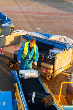 AMSTERDAM, NETHERLANDS - NOVEMBER 08: 08 Kasım 2014 tarihinde Hollanda 'nın Amsterdam Schiphol havaalanında bir uçaktan bavul indiren adam. Schiphol, Avrupa 'nın dördüncü büyük havaalanıdır..