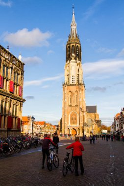 DELFT, NETHERLANDS - 10 Kasım 2014 'te insanlar Hollanda' nın Delft kentinde Yeni Kilise yakınlarında yürür. Yeni Kilise 1655 yılında tamamlandı ve 1584 yılından beri kraliyet mezarı olarak kullanılıyor..