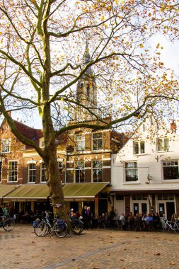 DELFT, NETHERLANDS - 10 Kasım 2014: Delf 'in ana meydanındaki açık hava restoranında oturan insanlar. Burası, bir sürü restoran, bar, mağaza ve kulübün yer aldığı popüler bir turistik yerdir.