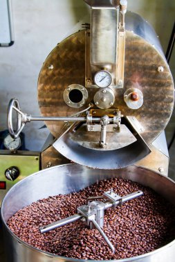 JUAYA, EL SALVADOR - 3 Mayıs 2014 'te Juayua, El Salvador' da soğutma silindirine dökülen büyük bir kahve kızartma makinesinden yeni kavrulmuş kahve çekirdekleri.