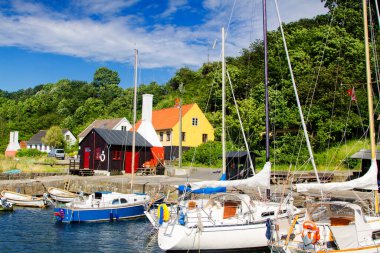 Typical Bornholm landscape with marina boats, smokehouse and half timbered architecture on a sunny day. clipart