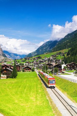 Red (glacier express) train heading through high mountain valley in switzerland alps on route from St. Moritz to Zermatt. clipart