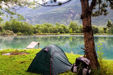 SION, SWitzERLAND - 12 Ağustos 2014 tarihinde Sion yakınlarındaki İsviçre Alplerinde yağmurlu bir sabahta gölün kenarında yalnız bir kamp alanı. Bisiklet ve kamp bir ülkeyi ziyaret etmenin popüler bir yoludur..