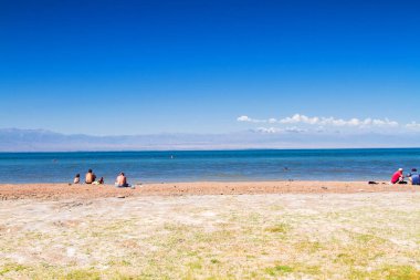Issyk Kul Gölü plajı, Kırgızistan, Orta Asya. Arkadaki Tian Shan Dağları.