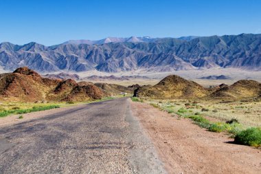 Güzel manzara - kurak arazide çorak dağlar arasındaki kıvrımlı yol canlı mavi gökyüzü, Tien Shan Sıradağları, Kırgızistan, Orta Asya