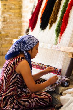 KHIVA, UZBEKISTAN - 14 Mart 2015: Khiva, Özbekistan, Orta Asya 'da el yapımı halı düğümleyen tanımlanamayan kadın dokumacı. Özbekistan el yapımı halılarla popüler..
