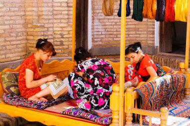 KHIVA, UZBEKISTAN - 14 Mart 2015: Khiva, Özbekistan, Orta Asya 'da el yapımı halı düğümleyen tanımlanamayan kadın dokumacı. Özbekistan el yapımı halılarla popüler..