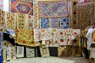 BÜKHARA, UZBEKISTAN - 14 Ağustos 2015: Buhara, Özbekistan, Orta Asya 'daki pazarda asılı eşarp ve halılar
