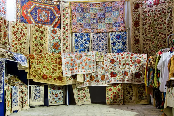 BÜKHARA, UZBEKISTAN - 14 Ağustos 2015: Buhara, Özbekistan, Orta Asya 'daki pazarda asılı eşarp ve halılar