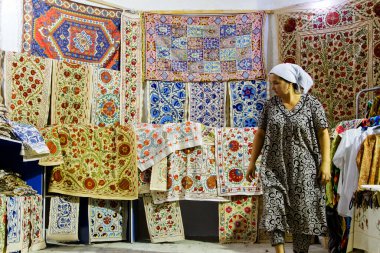 BÜKHARA, UZBEKISTAN - 15 Ağustos 2015 'te Buhara, Özbekistan, Orta Asya' daki pazarda asılı duran eşarp ve halılar.