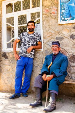 SARYTAG, TAJIKISTAN - 2 Ağustos 2015: Erkekler Fan Dağları 'ndaki basit bir mağazanın önündeki bankta oturuyorlar. Orta Asya