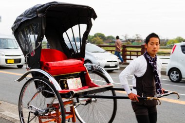 KYOTO, JAPONYA - 24 Kasım 2015 tarihinde Japonya 'nın Kyoto parkında çekilen triportörler. Erkekler tarafından çekilen Ricskshawlar turistler tarafından eski Kyoto 'yu (Gion) gezmenin popüler bir yoludur..