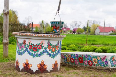 ZALIPIE, POLAND - 30 Nisan 2016: Renkli Köy 'deki bir kuyunun üzerinde bir kova - tüm bina ve nesnelerin geleneksel çiçek motifleriyle süslendiği miras parkı. Açık hava müzesi.