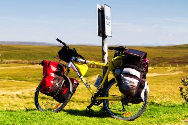SKYE ISLE, SCOTLAND - 15 Ağustos 2016: Yabancı bir gezi sırasında İskoç kırsalındaki çimlerin üzerinde panniers parketmiş bisiklet. Birleşik Krallık