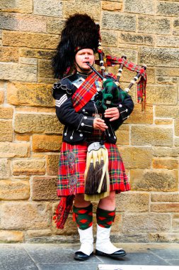 EDINBURGH, SCOTLAND, İngiltere - CIRCA AĞUSTust 2016: Geleneksel kırmızı ve siyah ekose elbise giymiş İskoç gaydacı. Edinburgh, İskoçya 'nın en popüler turizm şehri.