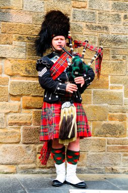EDINBURGH, SCOTLAND, İngiltere - CIRCA AĞUSTust 2016: Geleneksel kırmızı ve siyah ekose elbise giymiş İskoç gaydacı. Edinburgh, İskoçya 'nın en popüler turizm şehri.