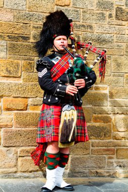 EDINBURGH, SCOTLAND, İngiltere - CIRCA AĞUSTust 2016: Geleneksel kırmızı ve siyah ekose elbise giymiş İskoç gaydacı. Edinburgh, İskoçya 'nın en popüler turizm şehri.