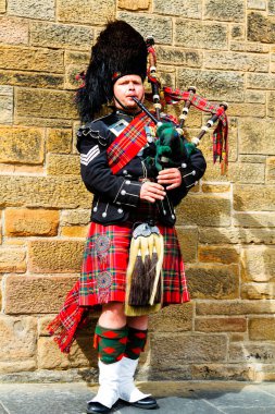 EDINBURGH, SCOTLAND, İngiltere - CIRCA AĞUSTust 2016: Geleneksel kırmızı ve siyah ekose elbise giymiş İskoç gaydacı. Edinburgh, İskoçya 'nın en popüler turizm şehri.