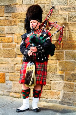 EDINBURGH, SCOTLAND, İngiltere - CIRCA AĞUSTust 2016: Geleneksel kırmızı ve siyah ekose elbise giymiş İskoç gaydacı. Edinburgh, İskoçya 'nın en popüler turizm şehri.