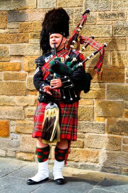EDINBURGH, SCOTLAND, İngiltere - CIRCA AĞUSTust 2016: Geleneksel kırmızı ve siyah ekose elbise giymiş İskoç gaydacı. Edinburgh, İskoçya 'nın en popüler turizm şehri.