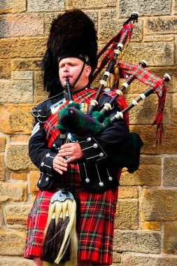 EDINBURGH, SCOTLAND, İngiltere - CIRCA AĞUSTust 2016: Geleneksel kırmızı ve siyah ekose elbise giymiş İskoç gaydacı. Edinburgh, İskoçya 'nın en popüler turizm şehri.