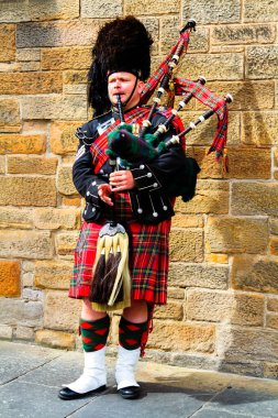 EDINBURGH, SCOTLAND, İngiltere - CIRCA AĞUSTust 2016: Geleneksel kırmızı ve siyah ekose elbise giymiş İskoç gaydacı. Edinburgh, İskoçya 'nın en popüler turizm şehri.