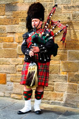 EDINBURGH, SCOTLAND, İngiltere - CIRCA AĞUSTust 2016: Geleneksel kırmızı ve siyah ekose elbise giymiş İskoç gaydacı. Edinburgh, İskoçya 'nın en popüler turizm şehri.