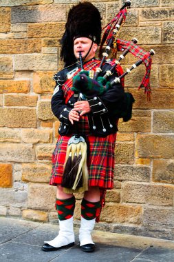 EDINBURGH, SCOTLAND, İngiltere - CIRCA AĞUSTust 2016: Geleneksel kırmızı ve siyah ekose elbise giymiş İskoç gaydacı. Edinburgh, İskoçya 'nın en popüler turizm şehri.
