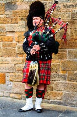 EDINBURGH, SCOTLAND, UK - CIRCA AUGUST 2016: Scottish bagpiper dressed in traditional red and black tartan dress. Edinburgh, the most popular tourist city destination in Scotland clipart