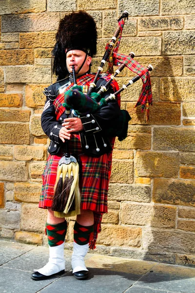 EDINBURGH, SCOTLAND, İngiltere - CIRCA AĞUSTust 2016: Geleneksel kırmızı ve siyah ekose elbise giymiş İskoç gaydacı. Edinburgh, İskoçya 'nın en popüler turizm şehri.
