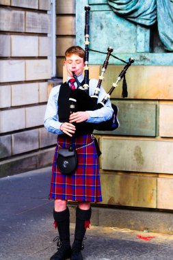 EDINBURGH, SCOTLAND, İngiltere - CIRCA AĞUSTust 2016: Geleneksel kırmızı ve siyah ekose elbise giymiş İskoç gaydacı. Edinburgh, İskoçya 'nın en popüler turizm şehri.