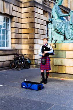 EDINBURGH, SCOTLAND, İngiltere - CIRCA AĞUSTust 2016: Geleneksel kırmızı ve siyah ekose elbise giymiş İskoç gaydacı. Edinburgh, İskoçya 'nın en popüler turizm şehri.