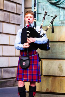 EDINBURGH, SCOTLAND, İngiltere - CIRCA AĞUSTust 2016: Geleneksel kırmızı ve siyah ekose elbise giymiş İskoç gaydacı. Edinburgh, İskoçya 'nın en popüler turizm şehri.
