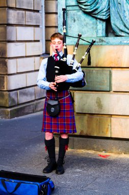 EDINBURGH, SCOTLAND, İngiltere - CIRCA AĞUSTust 2016: Geleneksel kırmızı ve siyah ekose elbise giymiş İskoç gaydacı. Edinburgh, İskoçya 'nın en popüler turizm şehri.