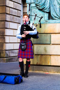 EDINBURGH, SCOTLAND, İngiltere - CIRCA AĞUSTust 2016: Geleneksel kırmızı ve siyah ekose elbise giymiş İskoç gaydacı. Edinburgh, İskoçya 'nın en popüler turizm şehri.