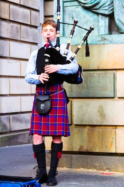 EDINBURGH, SCOTLAND, İngiltere - CIRCA AĞUSTust 2016: Geleneksel kırmızı ve siyah ekose elbise giymiş İskoç gaydacı. Edinburgh, İskoçya 'nın en popüler turizm şehri.