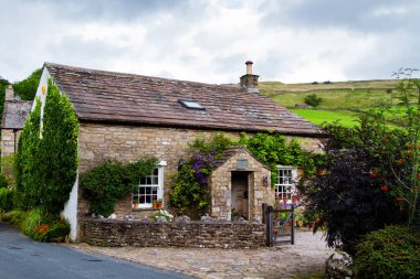 İngiltere 'de Yorkshire Dales Ulusal Parkı' ndaki nehrin kıyısındaki eski taş ev.