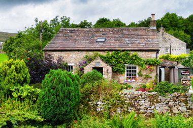 İngiltere 'de Yorkshire Dales Ulusal Parkı' ndaki nehrin kıyısındaki eski taş ev.