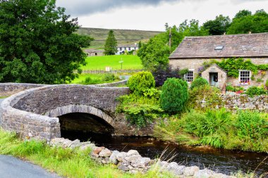 İngiltere 'de Yorkshire Dales Ulusal Parkı' ndaki nehrin kıyısındaki eski taş ev.