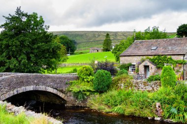 İngiltere 'de Yorkshire Dales Ulusal Parkı' ndaki nehrin kıyısındaki eski taş ev.