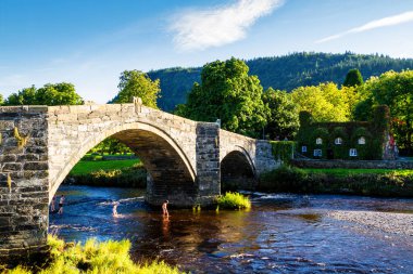 Pont Fawr, Conwy nehrinin karşısındaki ünlü ortaçağ taş köprüsü, Inigo Jones ve Tu-Hwnt-l 'r Bont tarafından inşa edildi - sarmaşık yapraklarıyla kaplı eski kulübe, Llanrwst, Caernarfon, Kuzey Galler, Birleşik Krallık