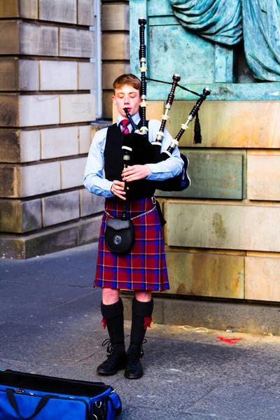EDINBURGH, SCOTLAND, İngiltere - CIRCA AĞUSTust 2016: Geleneksel kırmızı ve siyah ekose elbise giymiş İskoç gaydacı. Edinburgh, İskoçya 'nın en popüler turizm şehri.