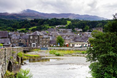 DOLGELLAU - WALES - 30 Ağustos 2017: İngiltere, İngiltere 'deki Snowdonia Ulusal Parkı' nda bulutlu bir günde nehir kenarında sakin bir taş kasaba