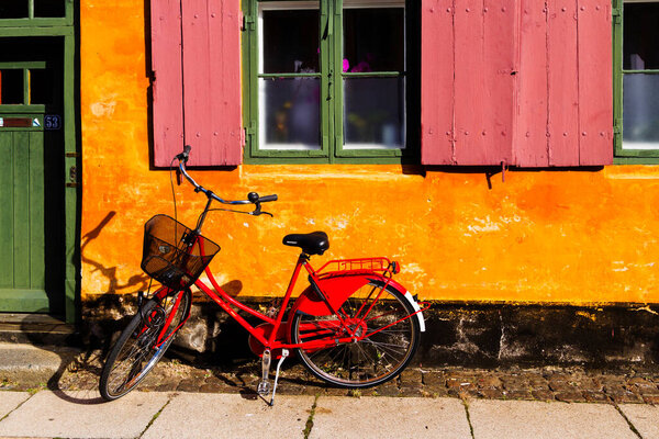 COPENHAGEN, DENMARK - OCTOBER 8, 2016: Nice old yellow houses of Nyboder, medieval district of Copenhagen, Denmark. Retro bicycled parked in front of the building on a pavement.