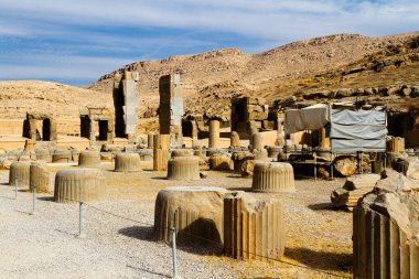 Persepolis UNESCO Dünya Mirasları Alanında İran 'ın Şiraz şehrinde bulutlu mavi gökyüzüne karşı levrek kabartması ile merdivenlerin arkasındaki Apadana ve Tachara Sarayı harabeleri. Orta Doğu, Asya