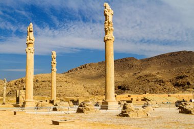 Persepolis UNESCO Dünya Mirasları Alanında İran 'ın Şiraz şehrinde bulutlu mavi gökyüzüne karşı levrek kabartması ile merdivenlerin arkasındaki Apadana ve Tachara Sarayı harabeleri. Orta Doğu, Asya