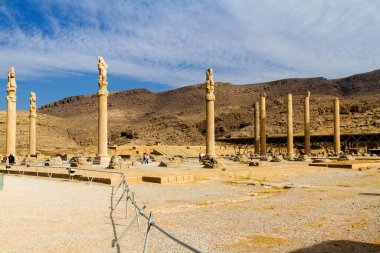 Persepolis UNESCO Dünya Mirasları Alanında İran 'ın Şiraz şehrinde bulutlu mavi gökyüzüne karşı levrek kabartması ile merdivenlerin arkasındaki Apadana ve Tachara Sarayı harabeleri. Orta Doğu, Asya