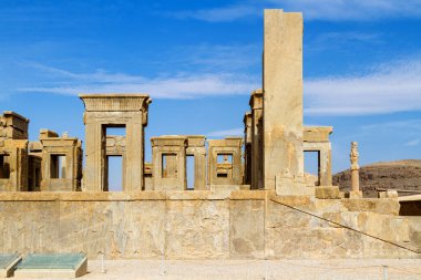 Persepolis UNESCO Dünya Mirasları Alanında İran 'ın Şiraz şehrinde bulutlu mavi gökyüzüne karşı levrek kabartması ile merdivenlerin arkasındaki Apadana ve Tachara Sarayı harabeleri. Orta Doğu, Asya