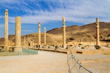 Persepolis UNESCO Dünya Mirasları Alanında İran 'ın Şiraz şehrinde bulutlu mavi gökyüzüne karşı levrek kabartması ile merdivenlerin arkasındaki Apadana ve Tachara Sarayı harabeleri. Orta Doğu, Asya
